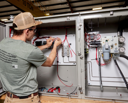 Side view of person in glasses and hat working on internals of machine