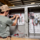 Side view of person in glasses and hat working on internals of machine